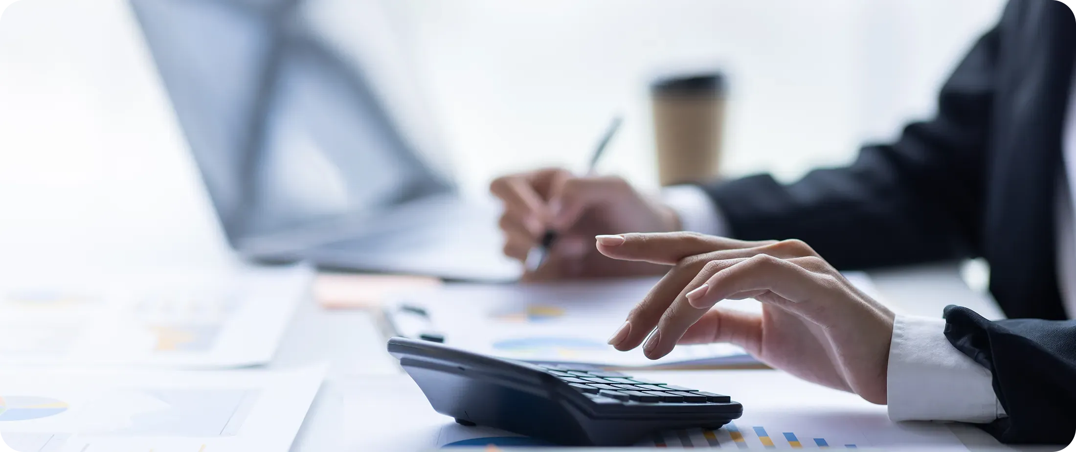 Finance professional reviewing transfer pricing data and charts while working with a calculator and laptop