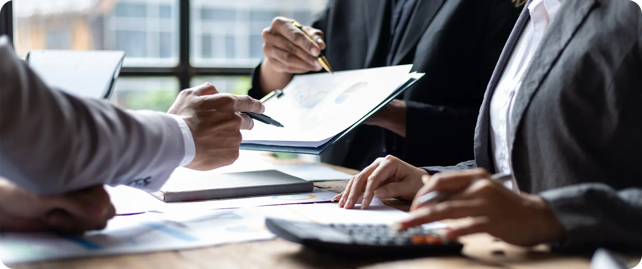 Professionals reviewing documents at a meeting table, with printed reports and a calculator visible