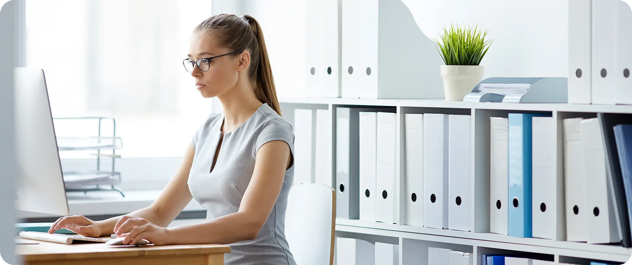 Tax professional working at a computer in a structured office environment with organized document files