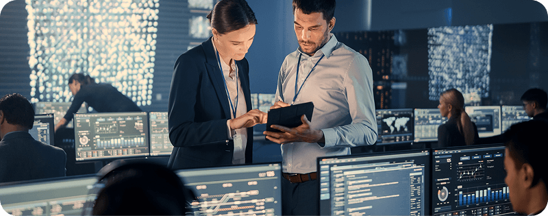 Team discussing data on digital screens in a modern office